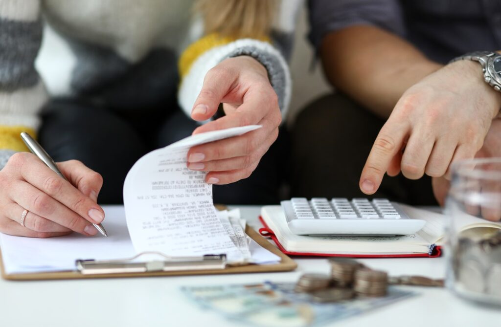 Photographie d'un couple faisant des calculs avec l'aide d'une calculette en lien avec la rénovation de maison 