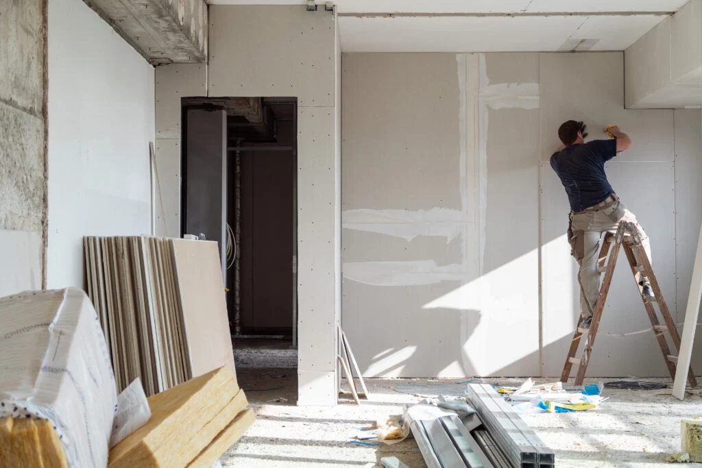 Photographie d'un artisan peintre en bâtiment en plein travail sur un chantier. En lien avec la rénovation de maison.